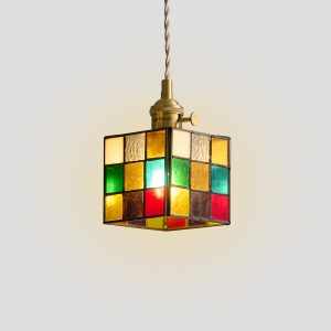 Vintage style multi-colored glass hanging lamp with brass frame hanging in a cozy living room reading corner