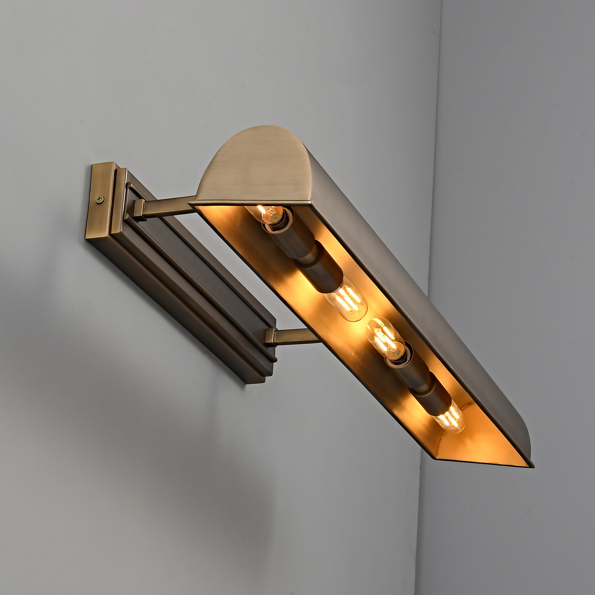 Antique Brass Picture Light 2 Close up side profile angle of the 4 light E12 antique brass picture light revealing the interior hooded shroud and glowing warm filament tubular LED bulbs.