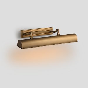 Front profile studio product shot of a 24 inch traditional antique brass art display light fixture casting a warm downward accent glow.