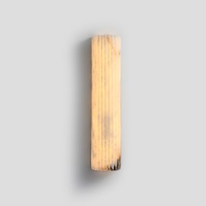 Fluted natural alabaster LED wall sconce lit up showing warm ambient glow.